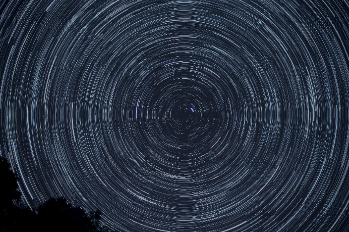 Time lapse astrophotograph showing stars swirling in the night sky as Earth rotates.